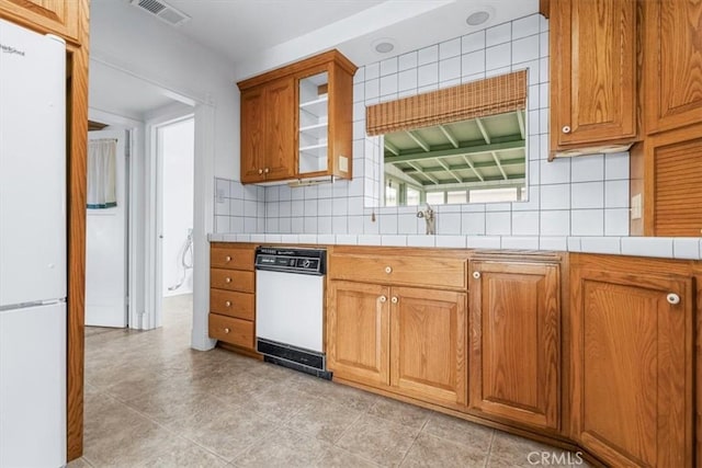 1851 Pacific Ave, Cayucos, CA 93430 - kitchen featuring white appliances, tile counters, brown cabinetry, backsplash, and glass insert cabinets