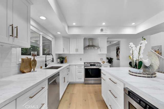 9500 Texhoma Ave, Northridge, CA 91325 - kitchen with appliances with stainless steel finishes, wall chimney range hood, light wood-type flooring, light stone counters, and white cabinetry