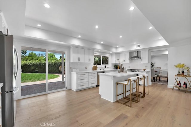 9500 Texhoma Ave, Northridge, CA 91325 - kitchen featuring wall chimney range hood, stainless steel appliances, a tray ceiling, a breakfast bar, and tasteful backsplash