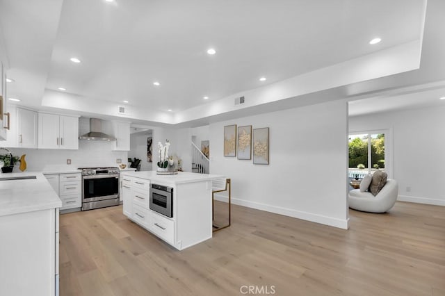 9500 Texhoma Ave, Northridge, CA 91325 - kitchen with stainless steel range, wall chimney exhaust hood, light wood-type flooring, a breakfast bar, and white cabinets