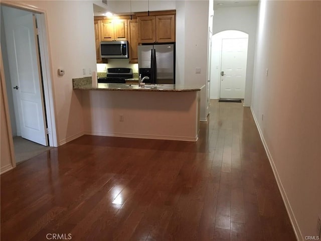 2750 Artesia Blvd Unit 341, Redondo Beach, CA 90278 - kitchen featuring appliances with stainless steel finishes, dark wood-style flooring, brown cabinetry, a peninsula, and stone counters