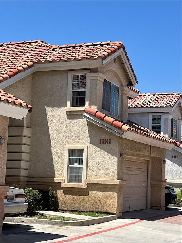 12143 Ferris Rd, El Monte, CA 91732 - view of property exterior featuring a tiled roof, an attached garage, stucco siding, and concrete driveway