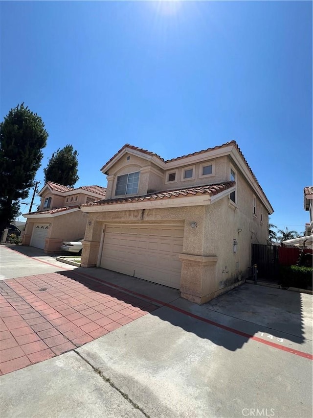 12143 Ferris Rd, El Monte, CA 91732 - view of side of home with stucco siding, a tiled roof, driveway, and an attached garage