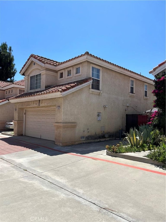 12143 Ferris Rd, El Monte, CA 91732 - view of front of house with stucco siding, a tile roof, an attached garage, and driveway
