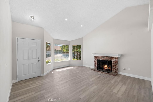 37537 Sabal Ct, Palmdale, CA 93552 - unfurnished living room with vaulted ceiling, wood finished floors, a textured ceiling, a fireplace, and recessed lighting
