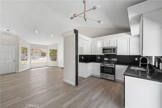 37537 Sabal Ct, Palmdale, CA 93552 - kitchen featuring appliances with stainless steel finishes, vaulted ceiling, dark countertops, open floor plan, and tasteful backsplash