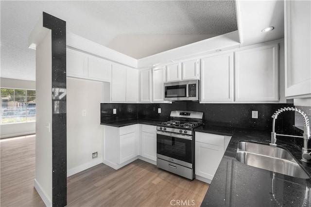 37537 Sabal Ct, Palmdale, CA 93552 - kitchen featuring appliances with stainless steel finishes, light wood-style floors, tasteful backsplash, white cabinetry, and a textured ceiling