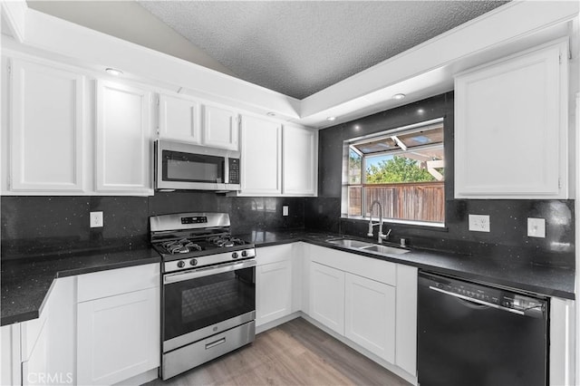 37537 Sabal Ct, Palmdale, CA 93552 - kitchen with appliances with stainless steel finishes, white cabinetry, decorative backsplash, a textured ceiling, and light wood-type flooring