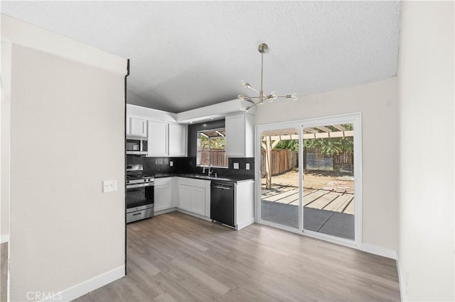 37537 Sabal Ct, Palmdale, CA 93552 - kitchen featuring appliances with stainless steel finishes, vaulted ceiling, a chandelier, white cabinetry, and backsplash