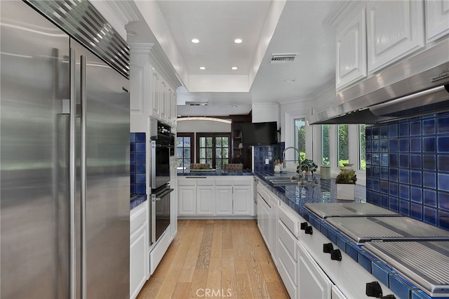 6137 Paseo La Vis, Woodland Hills, CA 91367 - kitchen featuring stainless steel built in fridge, under cabinet range hood, white cabinetry, light wood-style flooring, and tasteful backsplash