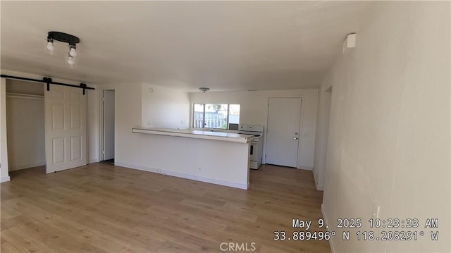 805 S Crane Ave, Compton, CA 90221 - kitchen with white range, a peninsula, light wood-style flooring, a barn door, and light countertops