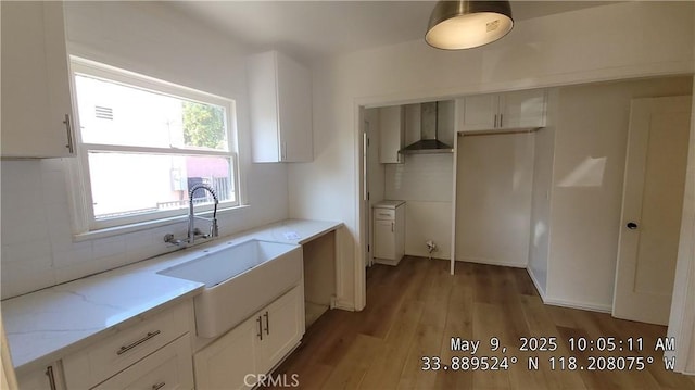 805 S Crane Ave, Compton, CA 90221 - kitchen featuring white cabinetry, light wood-style flooring, light stone countertops, wall chimney exhaust hood, and backsplash