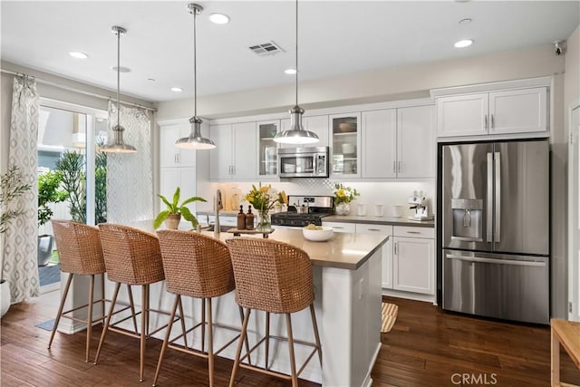 22088 Barrington Way, Saugus, CA 91350 - kitchen featuring appliances with stainless steel finishes, white cabinetry, an island with sink, glass insert cabinets, and dark wood-style floors