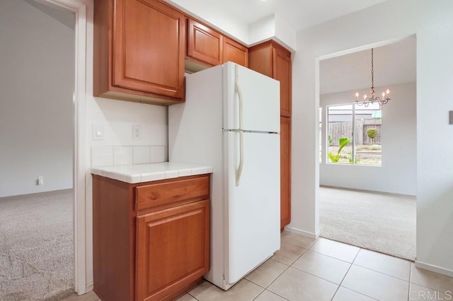 3694 Branch Ct, Oceanside, CA 92058 - kitchen featuring light colored carpet, freestanding refrigerator, a chandelier, brown cabinets, and light tile patterned flooring