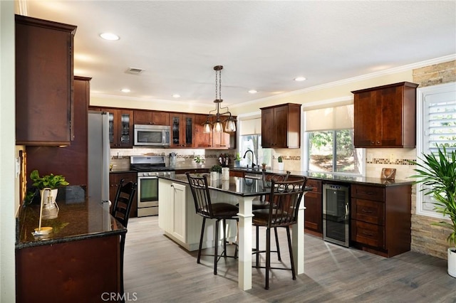 2350 Claudia St, Corona, CA 92882 - kitchen featuring appliances with stainless steel finishes, beverage cooler, plenty of natural light, a kitchen breakfast bar, and ornamental molding