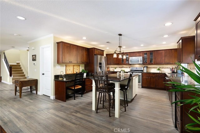 2350 Claudia St, Corona, CA 92882 - kitchen with stainless steel appliances, dark countertops, recessed lighting, a breakfast bar area, and ornamental molding