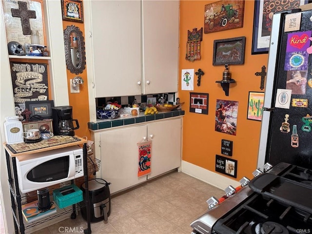 782 W 14th St, San Pedro, CA 90731 - kitchen with tile countertops, white microwave, freestanding refrigerator, and white cabinets