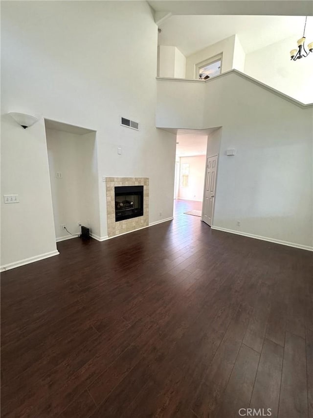 9 Greenwich Ct, Aliso Viejo, CA 92656 - unfurnished living room with dark wood-type flooring, high vaulted ceiling, a fireplace, and a chandelier