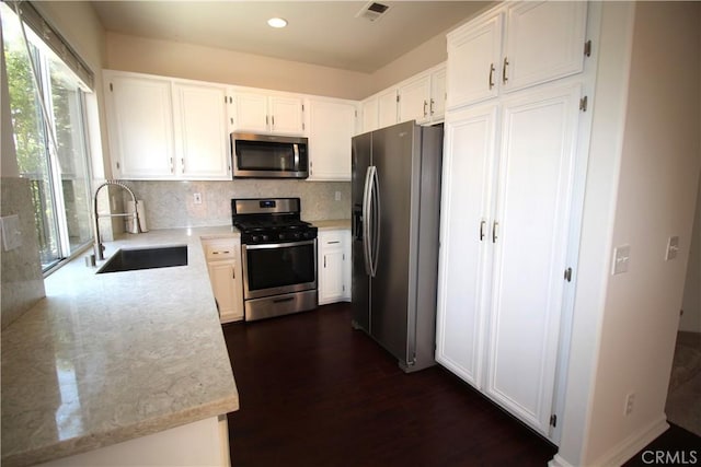 9 Greenwich Ct, Aliso Viejo, CA 92656 - kitchen with stainless steel appliances, white cabinets, tasteful backsplash, light stone counters, and dark wood-type flooring