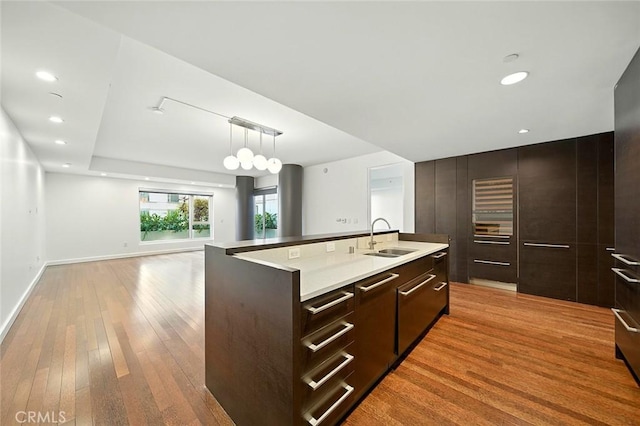 6250 Hollywood Blvd Unit 4D, Los Angeles, CA 90028 - kitchen featuring modern cabinets, light wood-style flooring, dark brown cabinetry, a center island with sink, and light countertops