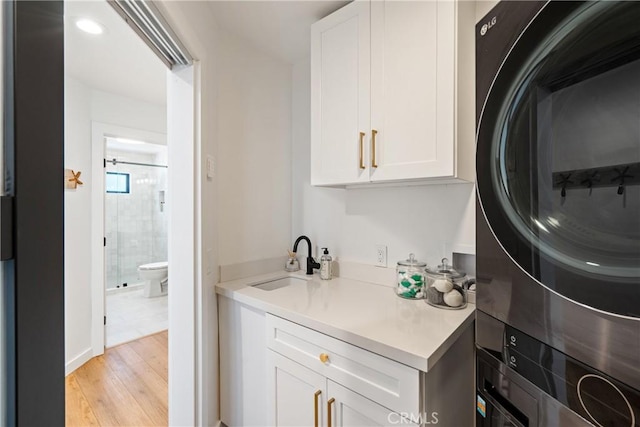 433 Emerald Bay Dr, Arroyo Grande, CA 93420 - laundry room with stacked washer and clothes dryer, cabinet space, and light wood-type flooring