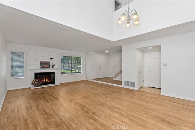 18 Denver Unit 71, Irvine, CA 92604 - unfurnished living room featuring light wood-type flooring, stairway, a brick fireplace, a chandelier, and recessed lighting
