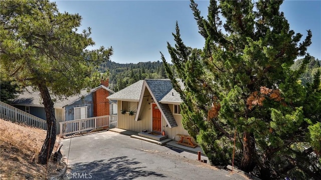 448 Delle Dr, Crestline, CA 92325 - view of front facade with a chimney, a shingled roof, and a forest view