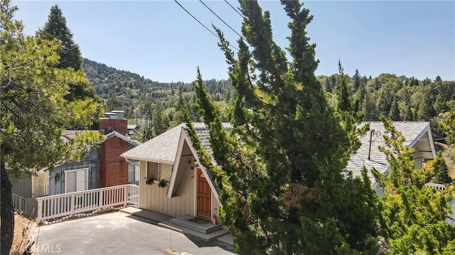 448 Delle Dr, Crestline, CA 92325 - exterior space featuring a wooded view, a chimney, and a shingled roof