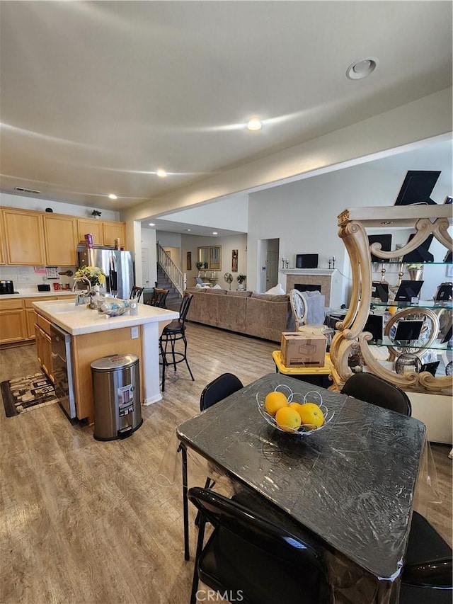 37882 Lopez Ln, Palmdale, CA 93552 - kitchen with stainless steel fridge, light brown cabinetry, dishwasher, a kitchen island, and light wood-style floors