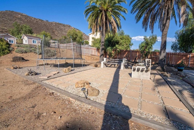 1415 Rex Ln, El Cajon, CA 92021 - fenced backyard featuring a trampoline, a mountain view, and a patio area