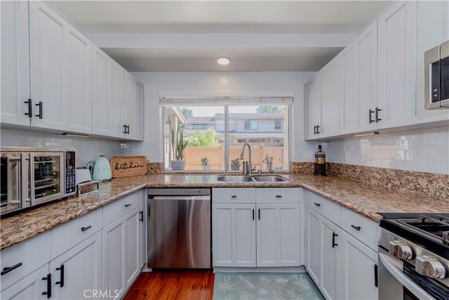 1755 Avenida Selva Unit 60, Fullerton, CA 92833 - kitchen featuring appliances with stainless steel finishes, white cabinets, tasteful backsplash, wood finished floors, and light stone counters