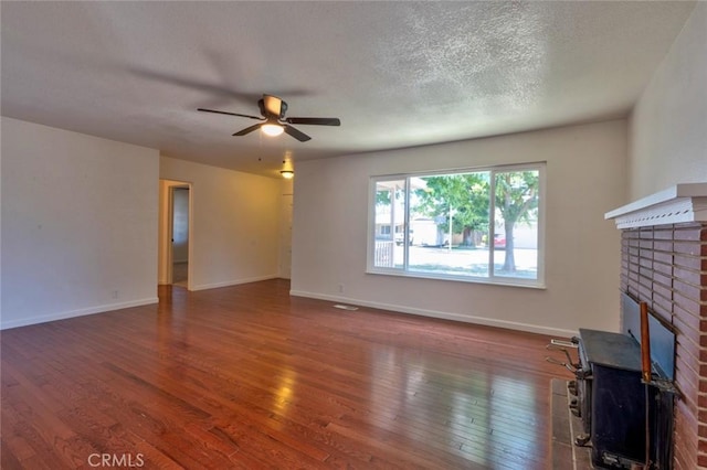 1101 Kensington Dr, Merced, CA 95340 - unfurnished living room with hardwood / wood-style floors, ceiling fan, a brick fireplace, and a textured ceiling