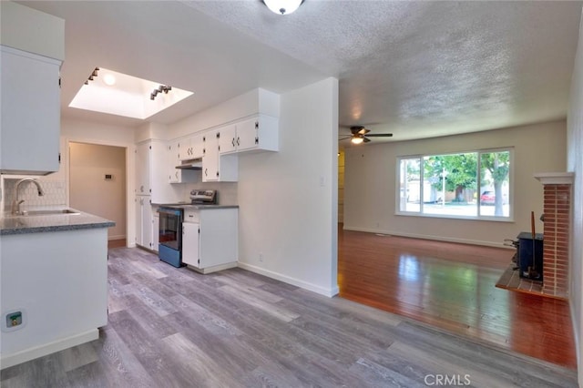 1101 Kensington Dr, Merced, CA 95340 - kitchen featuring range with electric cooktop, wood finished floors, a wood stove, ceiling fan, and white cabinetry