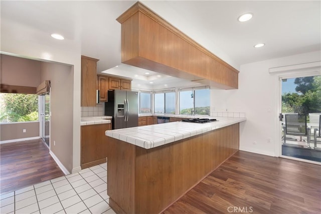 8 Via Subida, Rancho Palos Verdes, CA 90275 - kitchen featuring stainless steel appliances, tile counters, a peninsula, brown cabinets, and light wood-style floors
