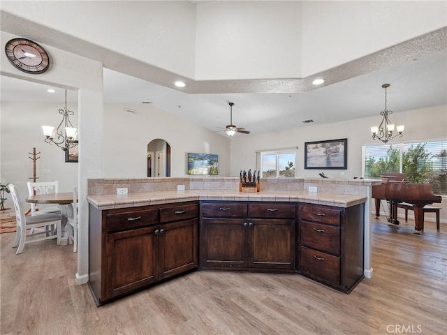 11823 Wintergreen Rd, Pinon Hills, CA 92372 - kitchen featuring a chandelier, light wood-style flooring, arched walkways, dark brown cabinetry, and vaulted ceiling
