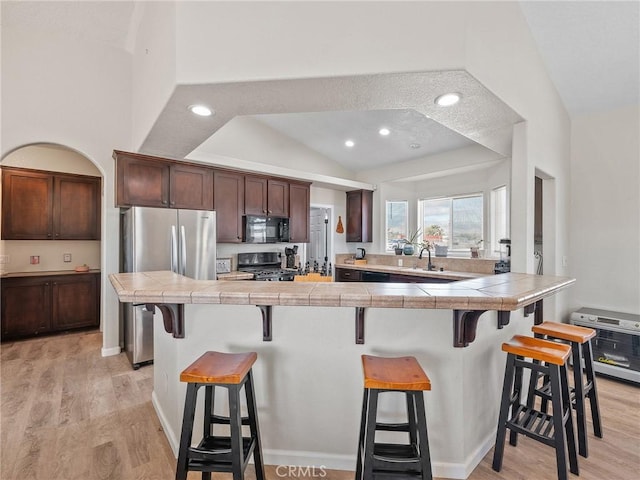 11823 Wintergreen Rd, Pinon Hills, CA 92372 - kitchen with black microwave, gas range oven, lofted ceiling, a kitchen bar, and freestanding refrigerator