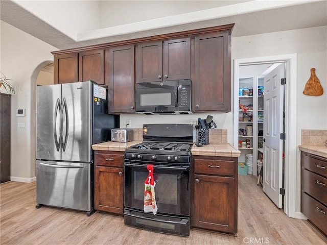 11823 Wintergreen Rd, Pinon Hills, CA 92372 - kitchen with black appliances, tile countertops, light wood-style flooring, and dark brown cabinetry