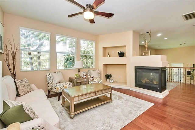 1180 Cornwell Dr, Fullerton, CA 92833 - living room with ceiling fan, wood finished floors, recessed lighting, built in shelves, and a multi sided fireplace