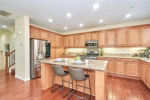 1180 Cornwell Dr, Fullerton, CA 92833 - kitchen featuring stainless steel appliances, a kitchen island, light stone counters, wood finished floors, and recessed lighting