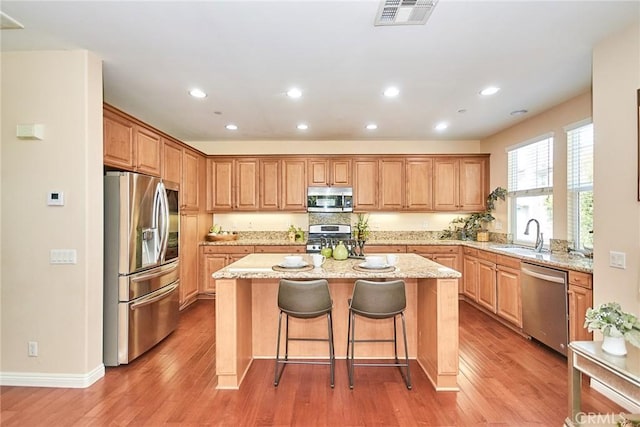 1180 Cornwell Dr, Fullerton, CA 92833 - kitchen with appliances with stainless steel finishes, a center island, light wood-style floors, light stone countertops, and recessed lighting