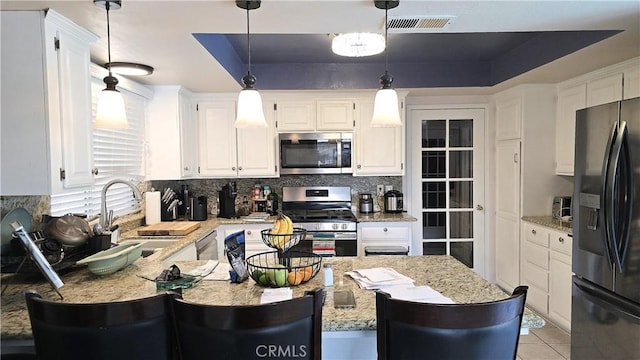 8467 Penfield Ave, Winnetka, CA 91306 - kitchen featuring stainless steel appliances, tasteful backsplash, white cabinets, pendant lighting, and light stone countertops