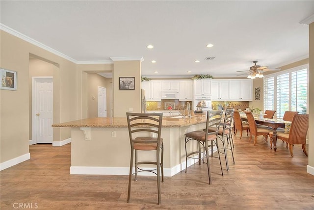 14182 Whitebark Ave, Chino, CA 91710 - kitchen with white appliances, ornamental molding, ceiling fan, a breakfast bar area, and light stone countertops