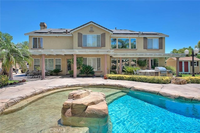 14182 Whitebark Ave, Chino, CA 91710 - back of property with a pergola, area for grilling, roof mounted solar panels, and stucco siding