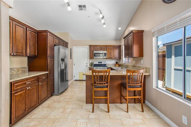 7471 Windrose Dr, Highland, CA 92346 - kitchen with appliances with stainless steel finishes, a peninsula, light stone countertops, vaulted ceiling, and a kitchen bar