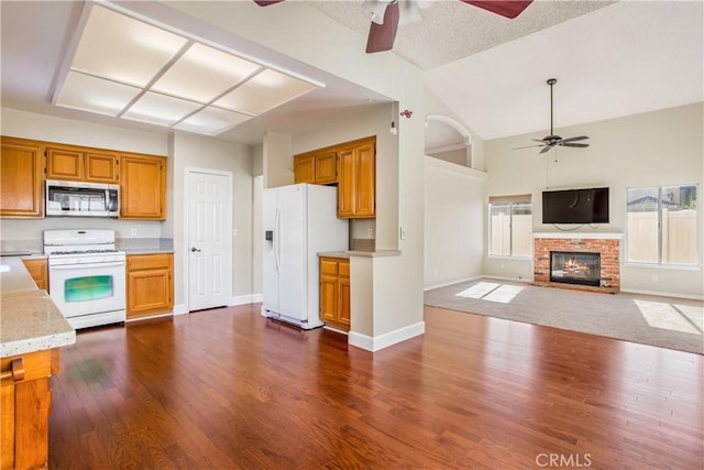 769 Amber Sky St, Banning, CA 92220 - kitchen with white appliances, ceiling fan, dark wood-style floors, a brick fireplace, and high vaulted ceiling