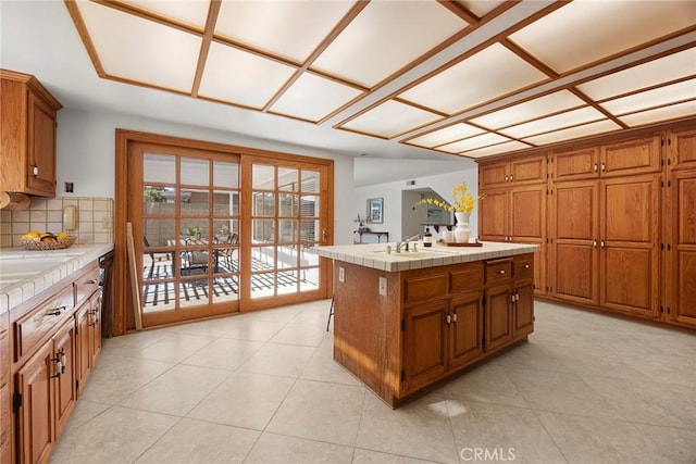 18312 Hartlund Ln, Huntington Beach, CA 92646 - kitchen with tile counters, brown cabinetry, tasteful backsplash, and light tile patterned flooring
