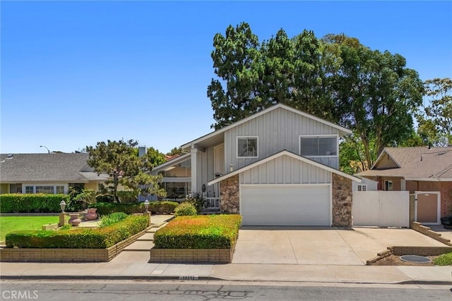 18312 Hartlund Ln, Huntington Beach, CA 92646 - view of front of house featuring board and batten siding, concrete driveway, a garage, stone siding, and a gate
