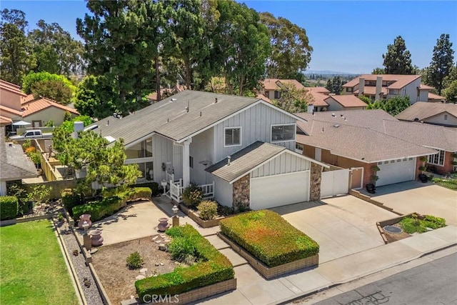 18312 Hartlund Ln, Huntington Beach, CA 92646 - view of front facade featuring an attached garage, board and batten siding, concrete driveway, stone siding, and a residential view