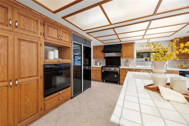 18312 Hartlund Ln, Huntington Beach, CA 92646 - kitchen with tile countertops, black appliances, wall chimney range hood, and tasteful backsplash