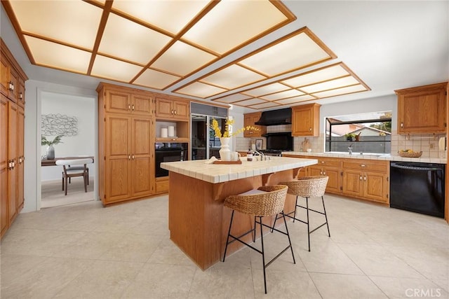 18312 Hartlund Ln, Huntington Beach, CA 92646 - kitchen with black appliances, tile countertops, tasteful backsplash, a kitchen island with sink, and a kitchen bar